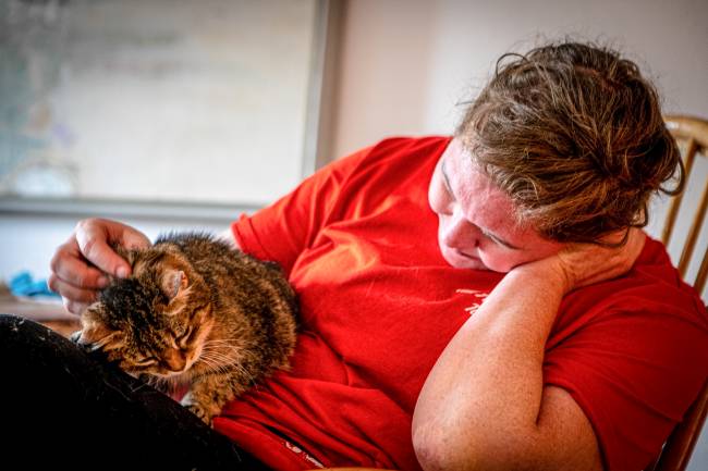 In der Katzenvilla streichelt Pflegerin Simone Schafhauser eine Katze auf ihrem Schoß