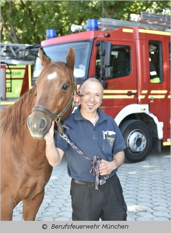 Feuerwehrmann mit Pferd vor Feuerwehrauto