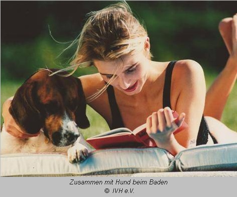 Frau mit Hund auf der Badedecke am See