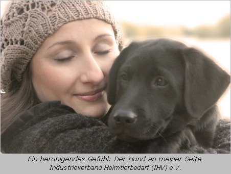Frau mit jungem Labrador auf dem Arm