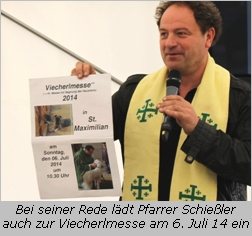 Pfarrer Schießler zeigt Plakat von der Viecherlmesse am 6. Juli 14